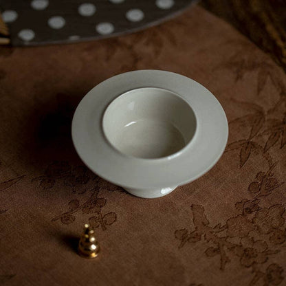 White ceramic bowl on a brown textured surface with a gold object nearby