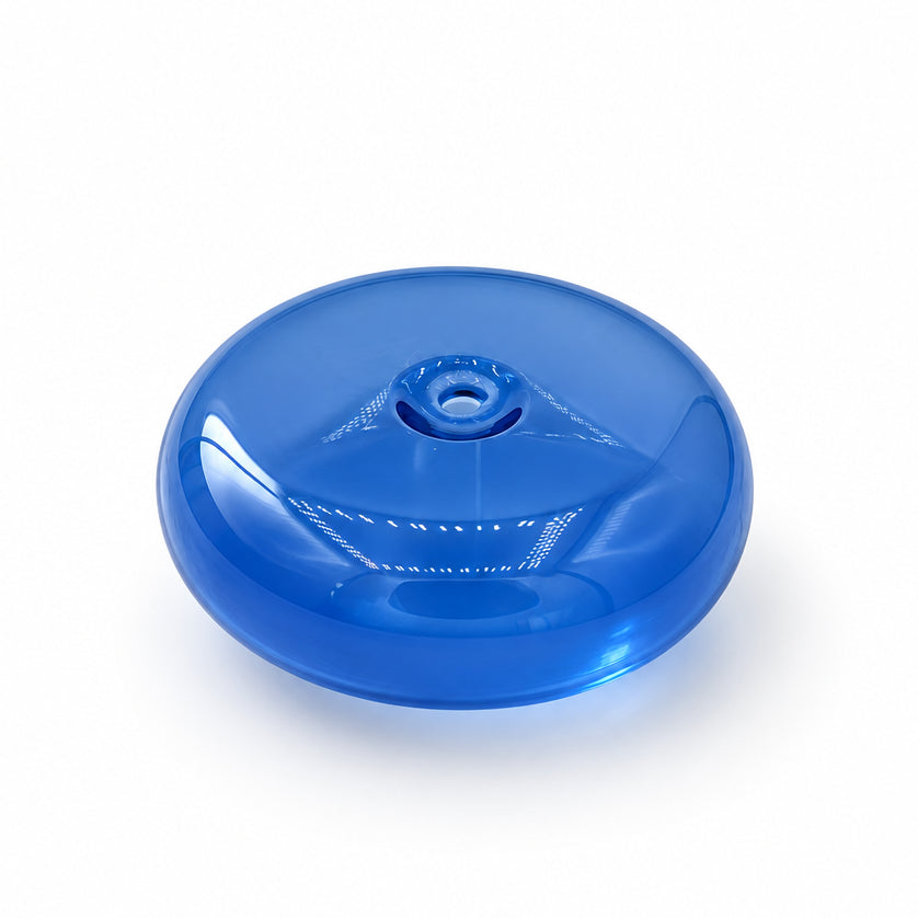 A translucent blue circular plastic cap or cover with a small hole in the center, resting on a white marble surface with gray veining.