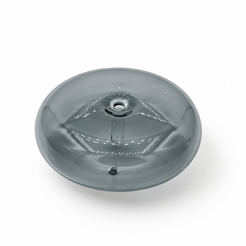 A small round translucent gray object with a central circular detail, placed on a white marble surface with gray veining.