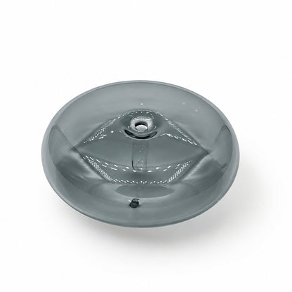 A small round translucent gray object with a central circular detail, placed on a white marble surface with gray veining.