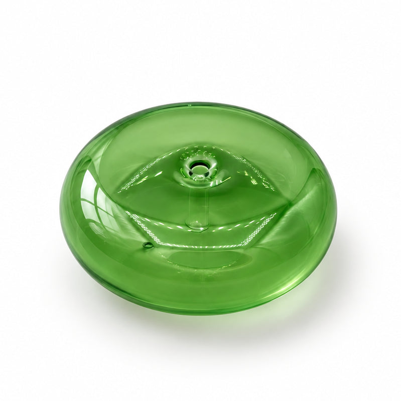 A translucent green glass button with a central hole, resting on a white marble surface with gray veining.