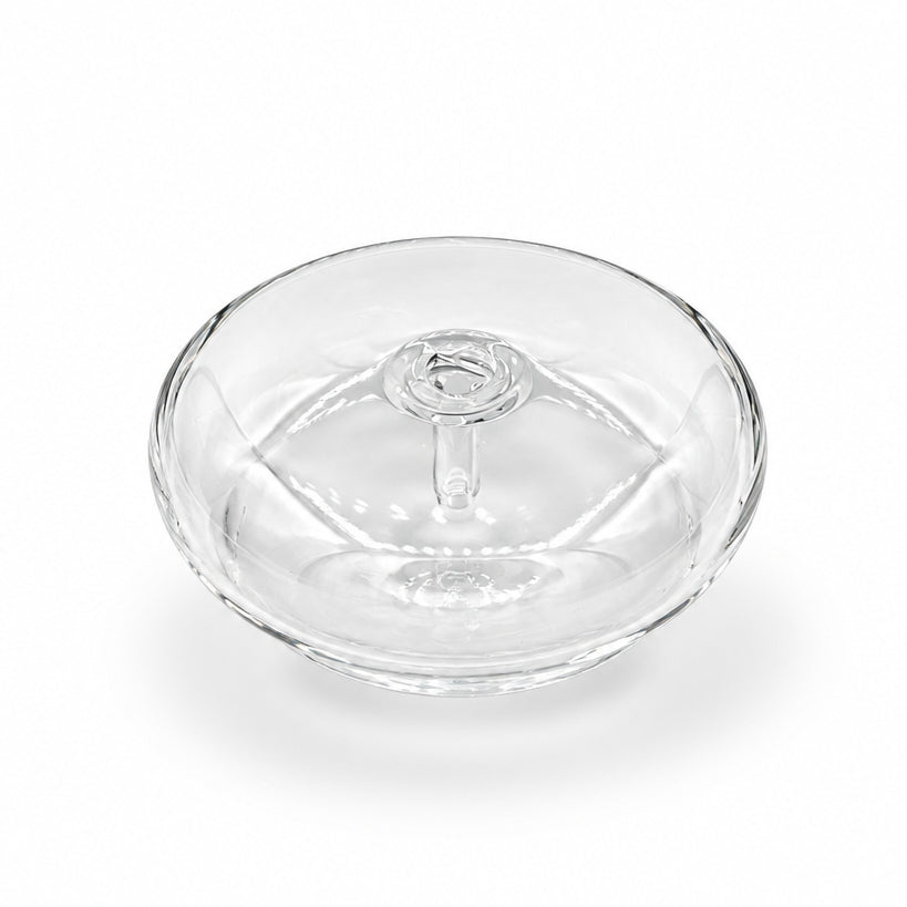A small clear glass or acrylic round container with a lid, placed on a white marble surface with gray veining.