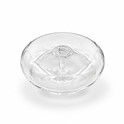 A small clear glass or acrylic round container with a lid, placed on a white marble surface with gray veining.