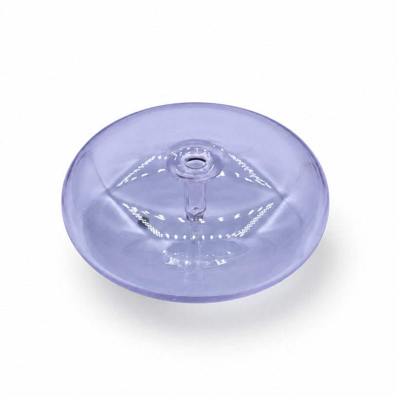A translucent light purple circular plastic piece with an embossed eye design, resting on a white and gray marble surface.