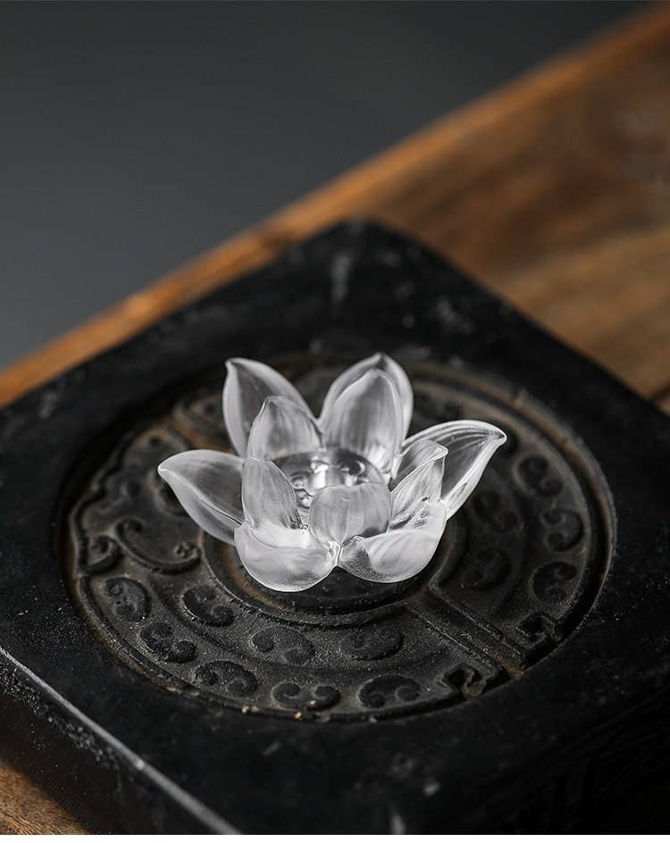 Clear lotus-shaped object on a dark, ornate base