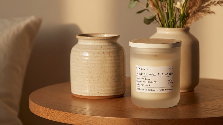 Candle and decorative jars on a wooden surface with a neutral background